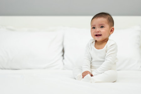 happy infant baby sitting on a bed