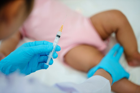doctor holding syringe and preparing vaccine giving injection to leg of infant babyの写真素材