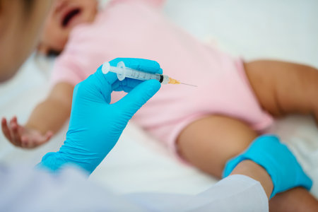 doctor holding syringe and preparing vaccine giving injection to leg of crying infant babyの写真素材