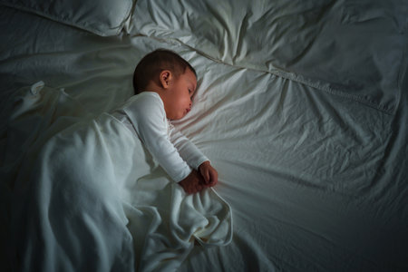 infant baby sleeping on a bed at nightの写真素材