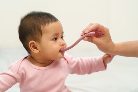 mother feeding a liquid medicine to sick infant baby with spoon