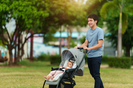 happy father pushing infant baby stroller and walking in the parkの写真素材