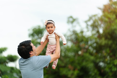 father holding and lifting with his infant baby in the parkの写真素材