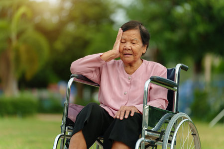 stressed senior woman suffering with headache while sitting in wheelchair at the parkの写真素材