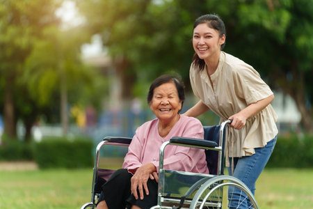 happy young granddaughter with senior woman in wheelchair at the parkの写真素材