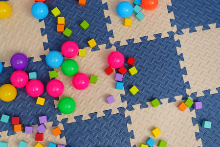 wooden block toy and colorful plastic balls on play mat or jigsaw floorの写真素材
