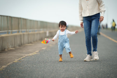 infant baby learn walking first step on a pathway with mother helping