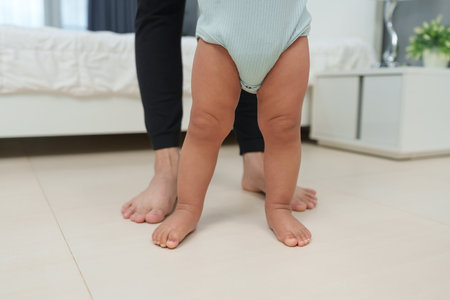 close up leg of infant baby walking with mother helping in homeの写真素材