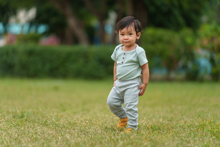 happy infant baby standing on a green grass in parkの写真素材