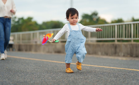 infant baby learn walking first step on a pathway with mother helpingの写真素材