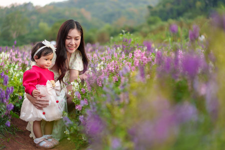 mother and her daughter enjoying Angelonia flower blooming in fieldの写真素材