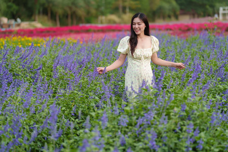 beautiful woman in a dress enjoying blooming lavender flower fieldの写真素材