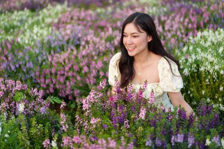 beautiful woman in a dress enjoying Angelonia flower blooming in fieldの写真素材
