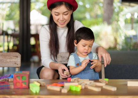 toddler girl playing toy with her mother on a tableの写真素材