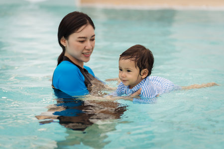 happy mother teaching her daughter swimming in poolの写真素材