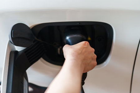 close up of hand charging environmentally friendly zero emission electric car at homeの写真素材
