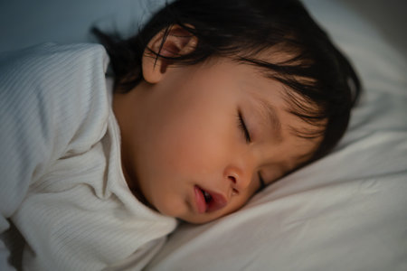close up toddler baby sleeping on a bed at nightの写真素材