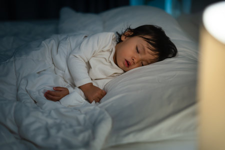 toddler baby sleeping on a bed at nightの写真素材