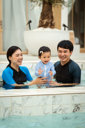 happy family. father and mother with small daughter playing in swimming pool.の写真素材
