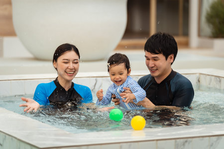 happy family. father and mother with small daughter playing in swimming pool.の写真素材
