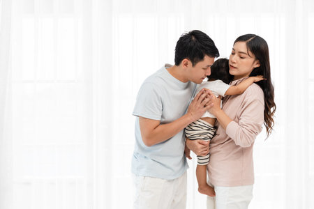 father and mother holding and hugging with toddler baby on white window background. happy family conceptの写真素材