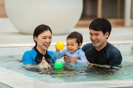 happy family. father and mother with small daughter playing in swimming pool.の写真素材