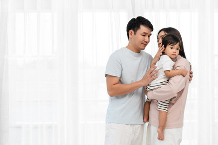 father and mother holding and hugging with toddler baby on white window background. happy family conceptの写真素材