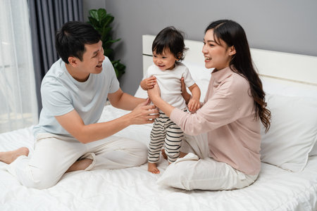 happy family, mother and father with toddler baby on a bedの写真素材