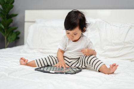 toddler baby using digital tablet pc on a bedの写真素材