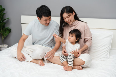 happy family, mother and father with toddler baby on a bedの写真素材
