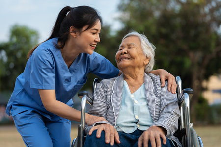 happy nurse take care and talking with senior woman patient in wheelchair at the park, friendly caregiverの写真素材