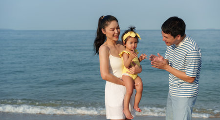 toddler baby girl with her father and mother. happy family on the sea beachの写真素材