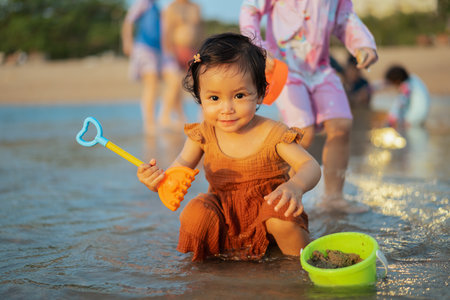 happy toddler baby girl playing toy and water on the sea beachの写真素材
