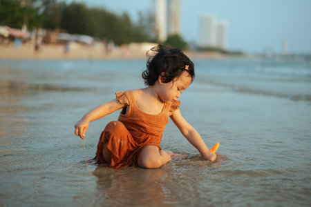 happy toddler baby girl playing toy and water on the sea beachの写真素材