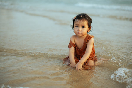 happy toddler baby girl playing sand and water on the sea beachの写真素材