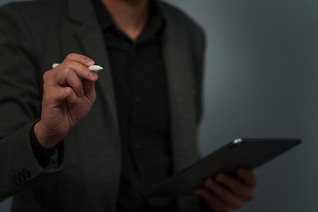 businessman hand using pen stylus writing on empty virtual screen with digital tabletの写真素材