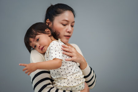 mother holding and comforting her crying toddler babyの写真素材
