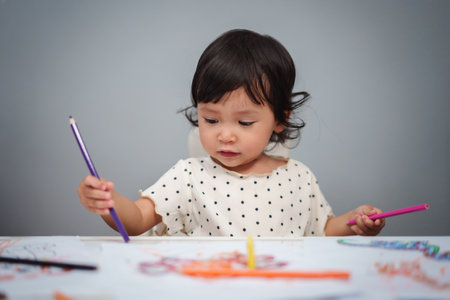 toddler baby playing and training to drawing with colored pencil on the tableの写真素材