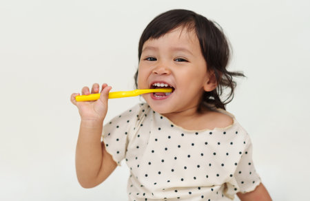 happy toddler girl brushes her teeth with a smileの写真素材