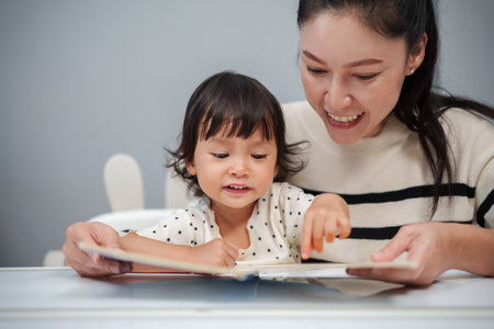 mother read story in the book for toddler baby on the tableの写真素材