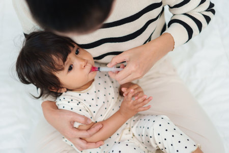 mother feeding a liquid medicine to baby girl by syringe. sick toddlerの写真素材
