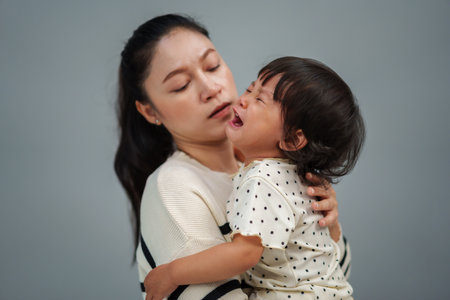 mother holding and comforting her crying toddler babyの写真素材