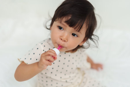 baby girl takes syrup medicine by herself. sick toddlerの写真素材