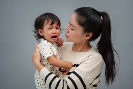 mother holding and comforting her crying toddler babyの写真素材