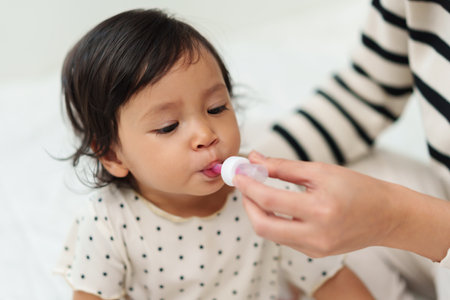 mother feeding a liquid medicine to sick toddler girl with dropperの写真素材
