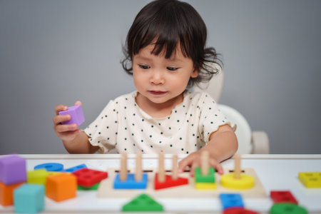 toddler baby girl playing with wooden educational geometric on the tableの写真素材