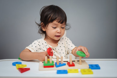 toddler baby girl playing with wooden educational geometric on the tableの写真素材