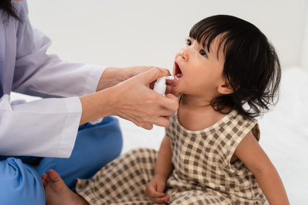 doctor spraying medicine in teeth of toddler girl. baby decayed tooth protect conceptの写真素材