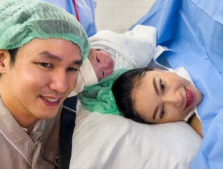 first sight of father and mother with their newborn baby after the Cesarean section in operation room. happy family conceptの写真素材