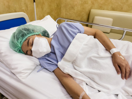 pregnant woman patient wearing medical mask while sleeping on a bed in hospitalの写真素材